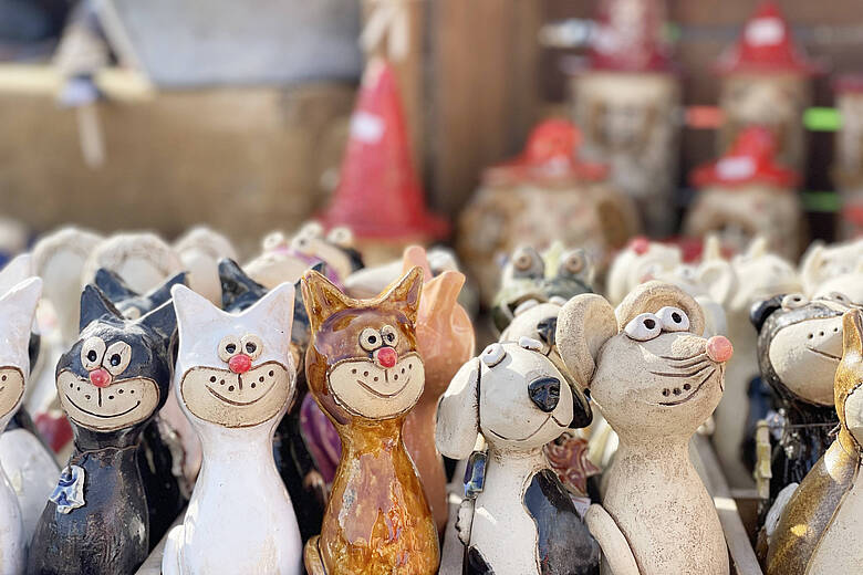Fröhlich bemalte Katzen-, Hunde- und Mäusefiguren aus Keramik auf einem Marktstand beim Handwerkermarkt.