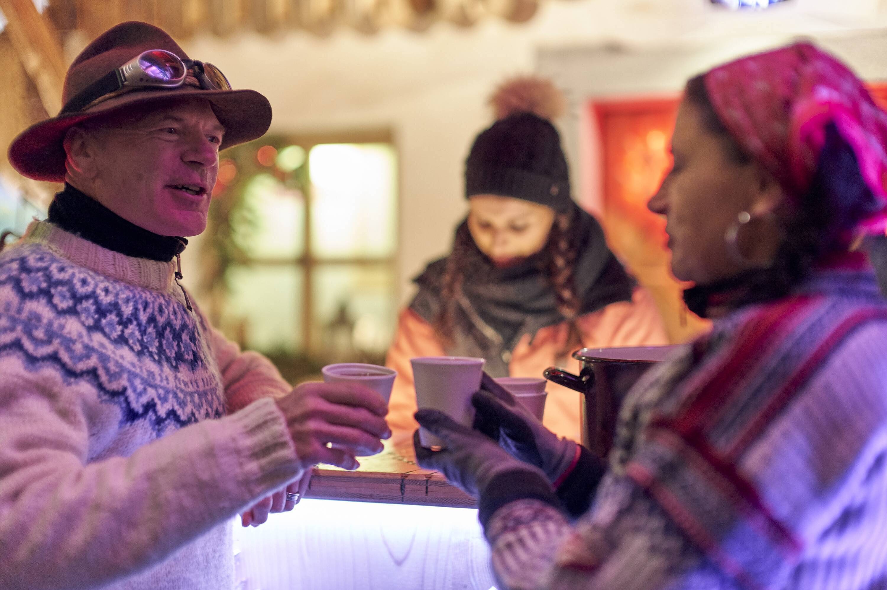 Zwei Gäste stoßen mit Glühwein beim Winterevent im JOSKA Glasparadies an